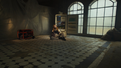 a woman sitting on the floor in front of a refrigerator