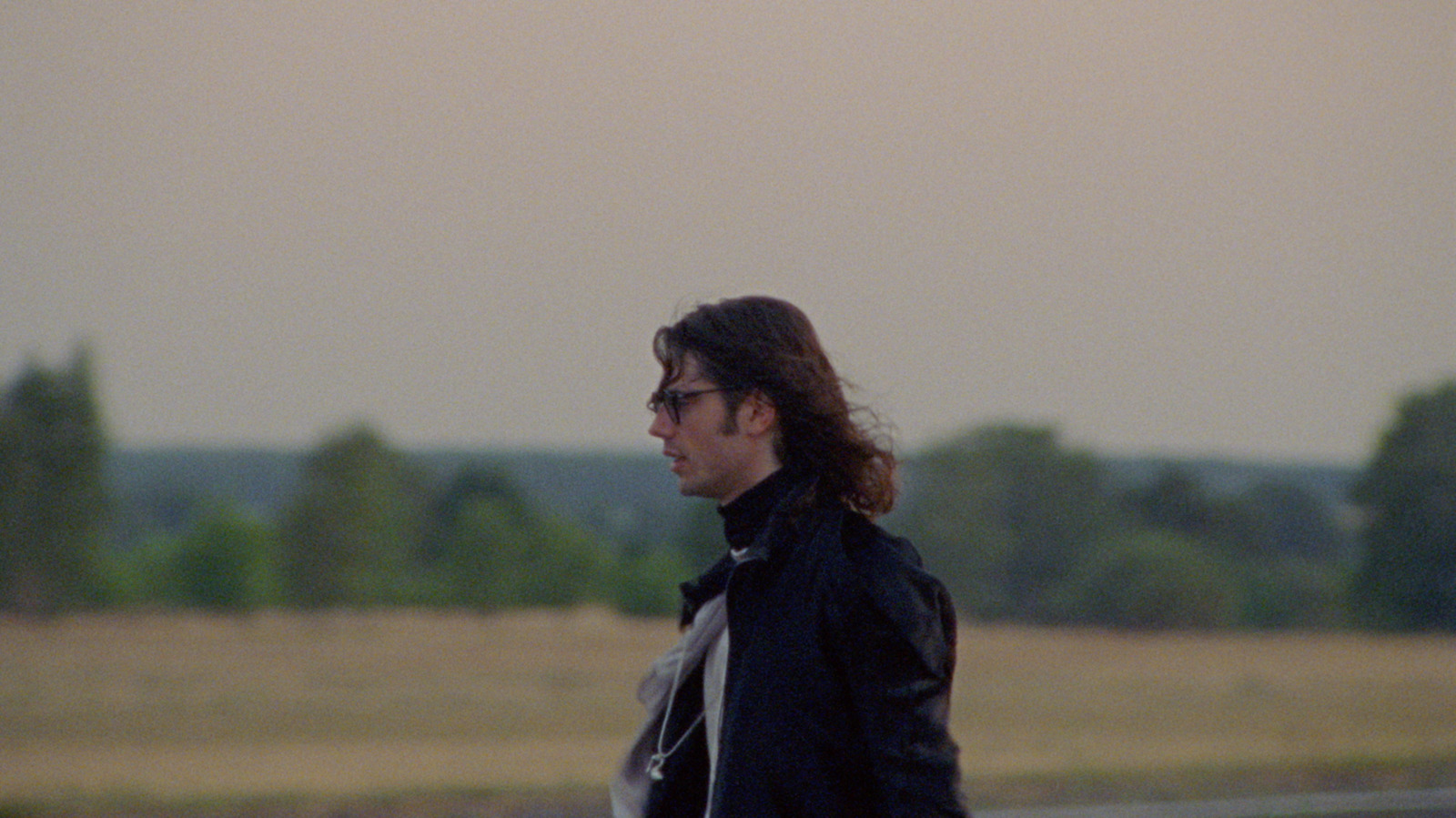 a man in a black jacket is walking down the street