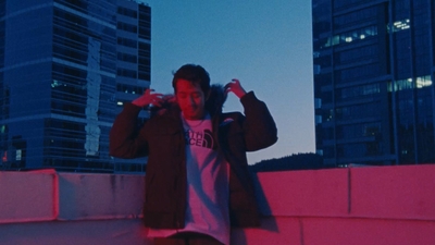 a man leaning against a wall in front of tall buildings