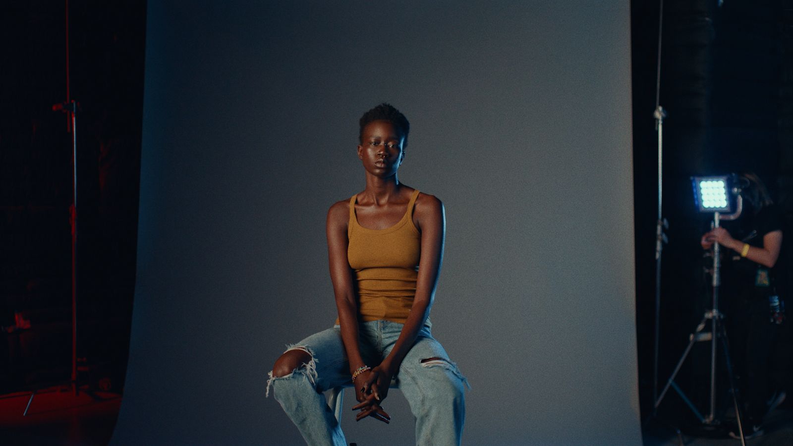 a woman sitting on a stool in front of a camera