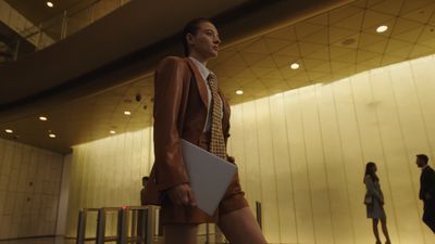 a woman in a suit and tie walking in a lobby