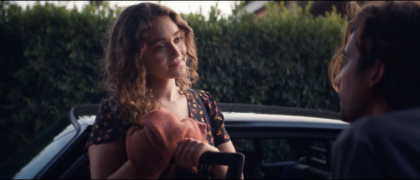 a woman standing next to a man in front of a car