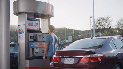 a man standing next to a car at a gas pump