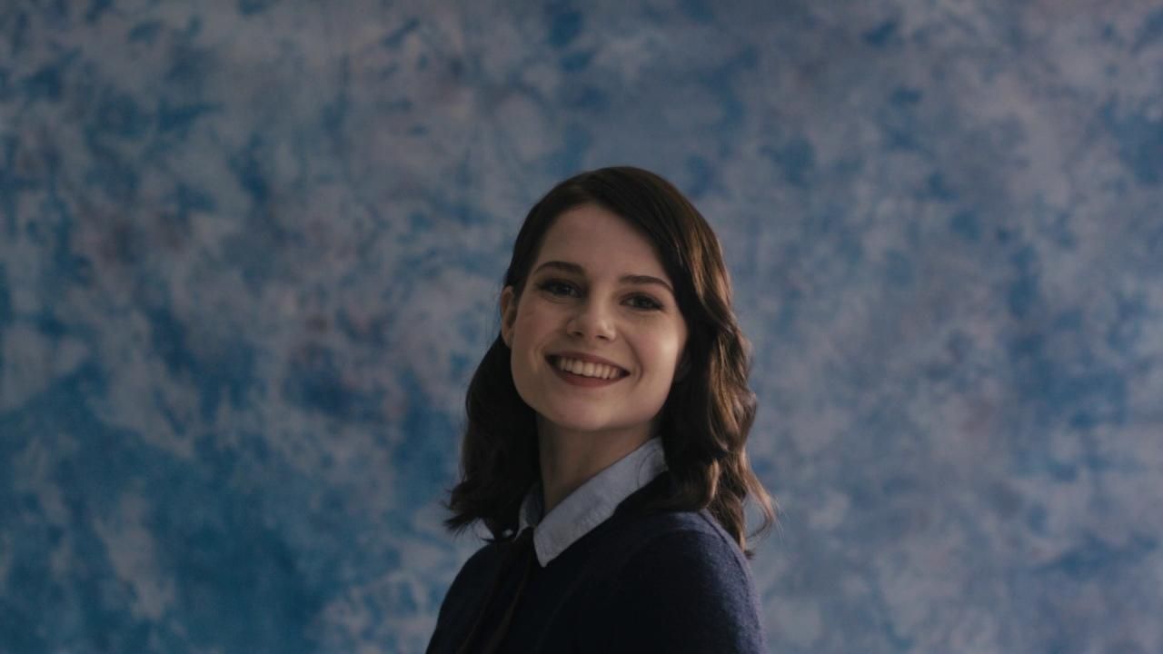 a woman smiling in front of a blue background