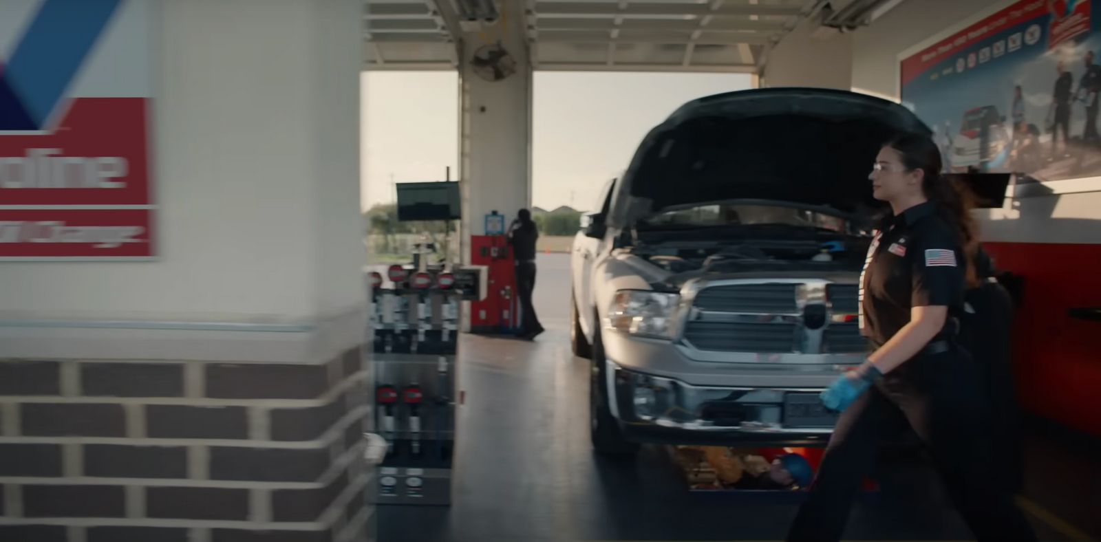 a woman is walking towards a car in a garage