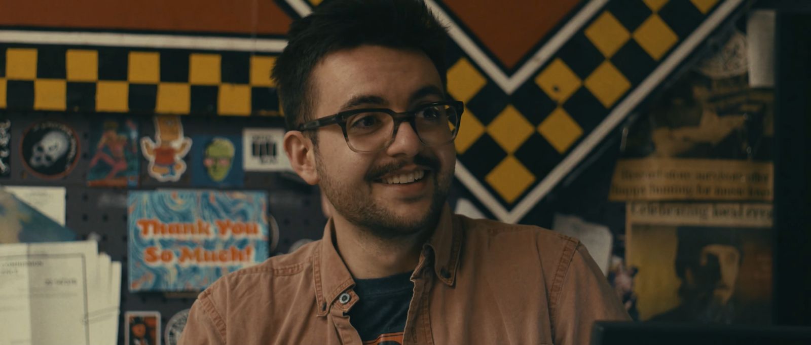 a man wearing glasses and a brown shirt