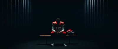 a football player sitting on a bench in the dark