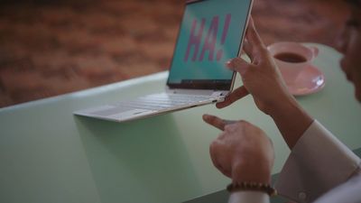 a person sitting at a table using a laptop computer