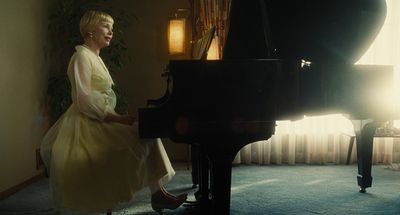 a woman sitting at a piano in front of a window