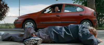 a couple of people laying on the ground next to a car