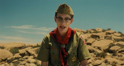 a young boy wearing a green uniform and a red scarf