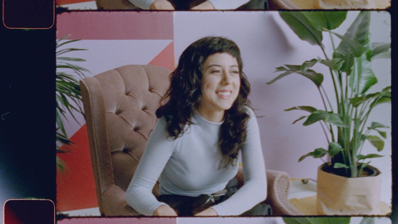 a woman sitting in a chair next to a potted plant