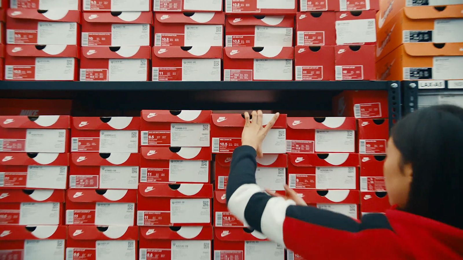 a woman reaching up to a wall of red boxes