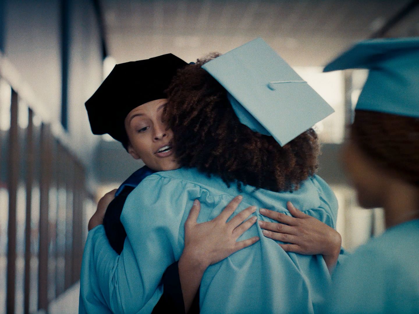 a woman hugging another woman in a graduation gown