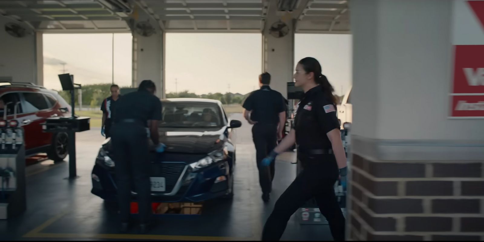 a group of people standing around a car in a garage