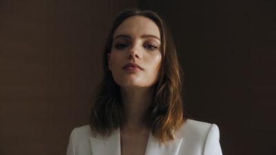 a woman in a white suit looks off into the distance