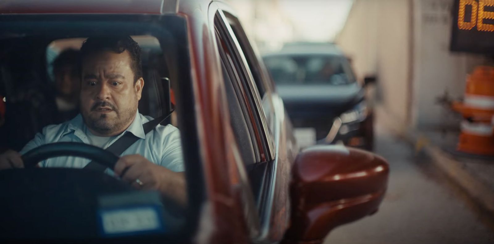 a man driving a red car down a street