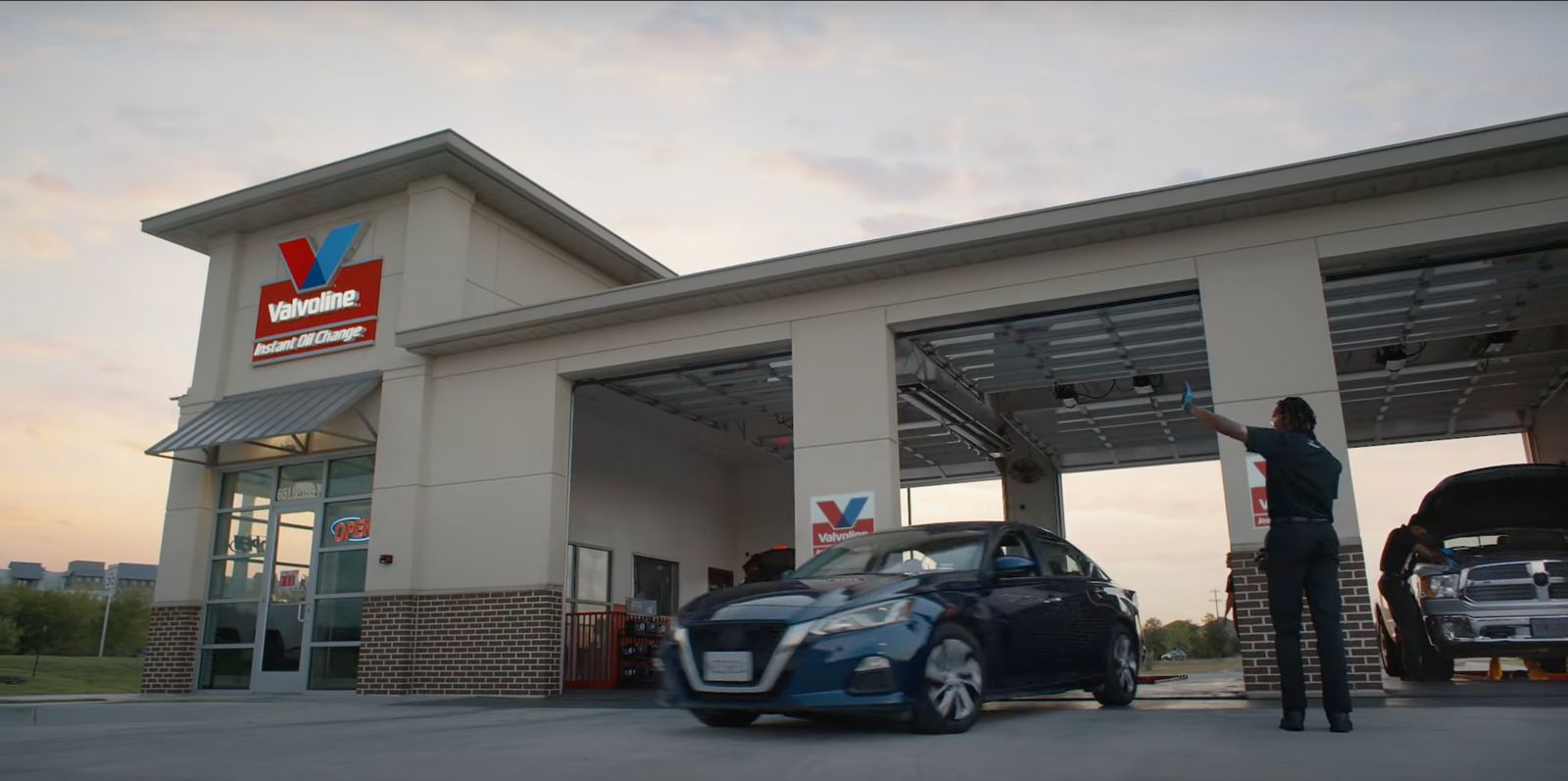 a man standing next to a blue car in front of a building