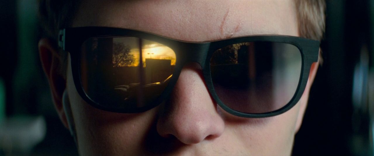 a man wearing sunglasses with the reflection of a building in it