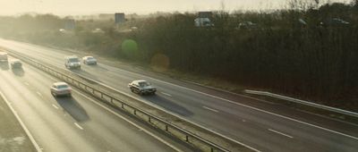 a highway filled with lots of traffic next to a forest