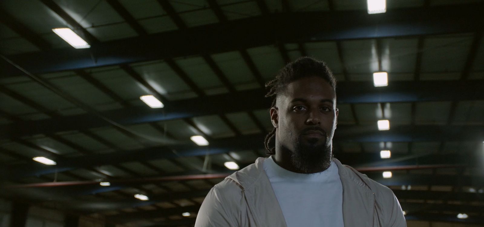 a man in a white shirt and suspenders standing in a warehouse