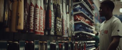 a man standing in front of a rack of baseball bats