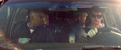 three people sitting in a car in the sun