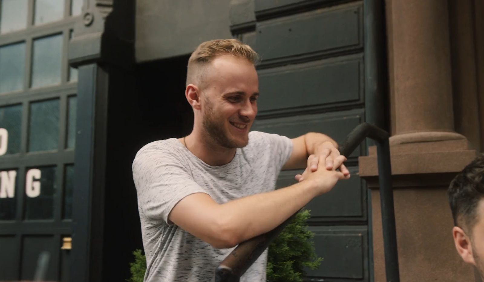 a man holding onto a pole in front of a building