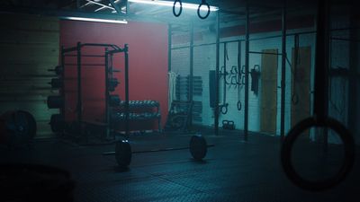 a dimly lit gym room with a barbell rack