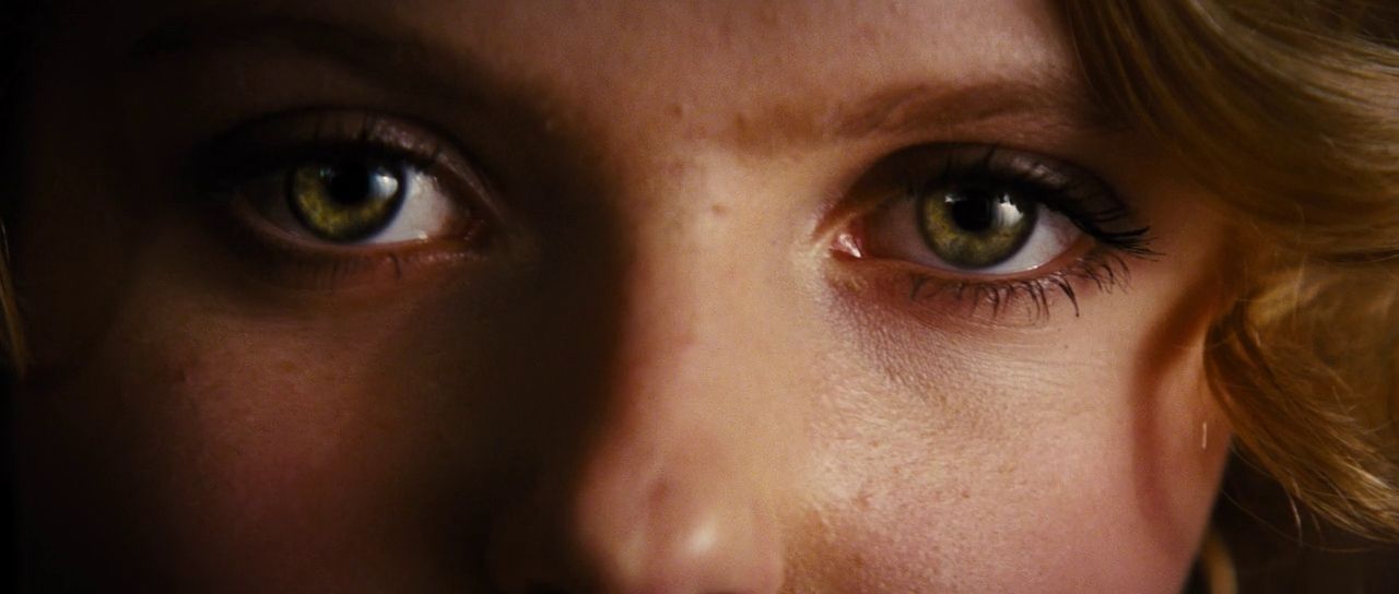 a close up of a woman's face with green eyes