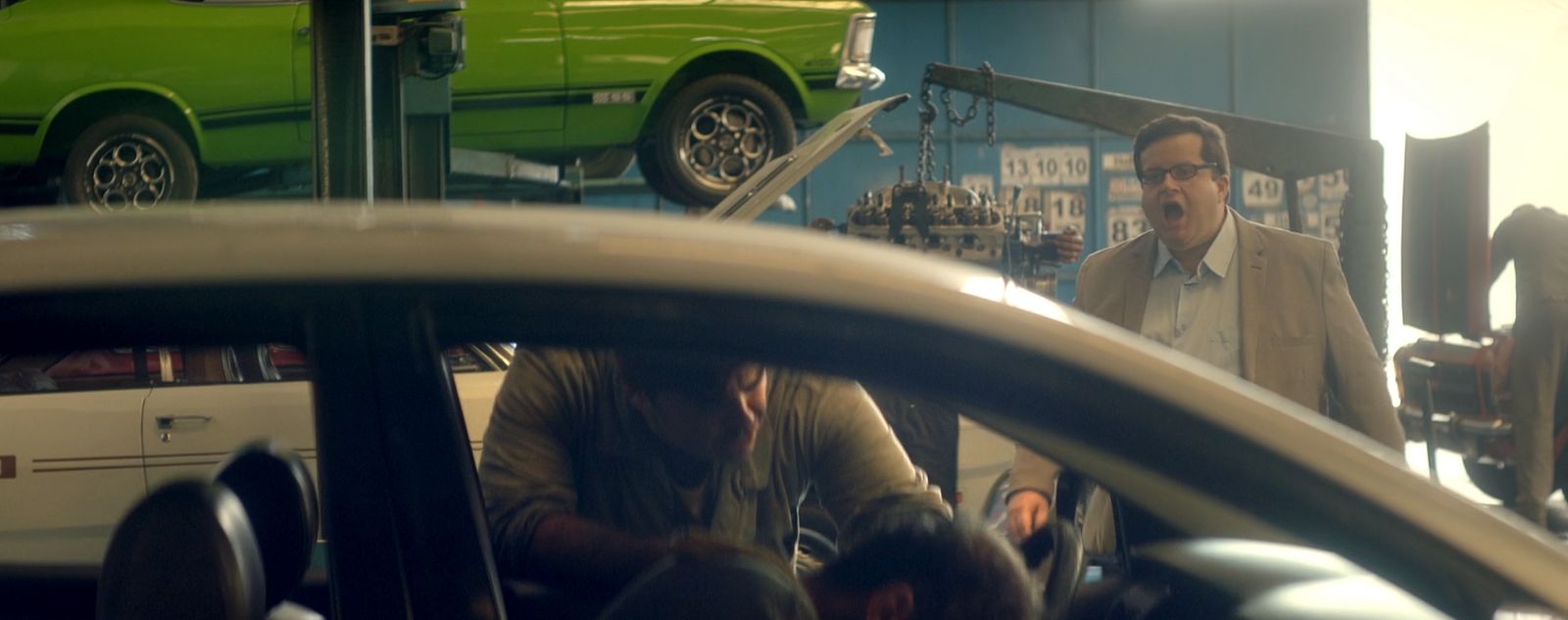 a man standing next to a green car in a garage