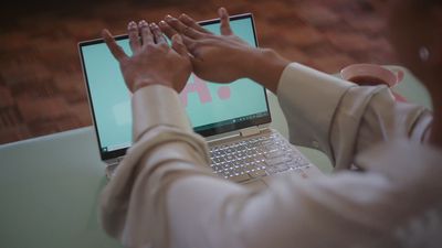 a person sitting at a table using a laptop computer