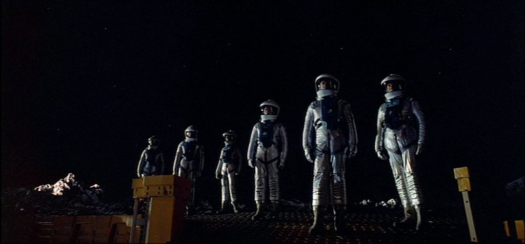 a group of people in space suits standing on a surface