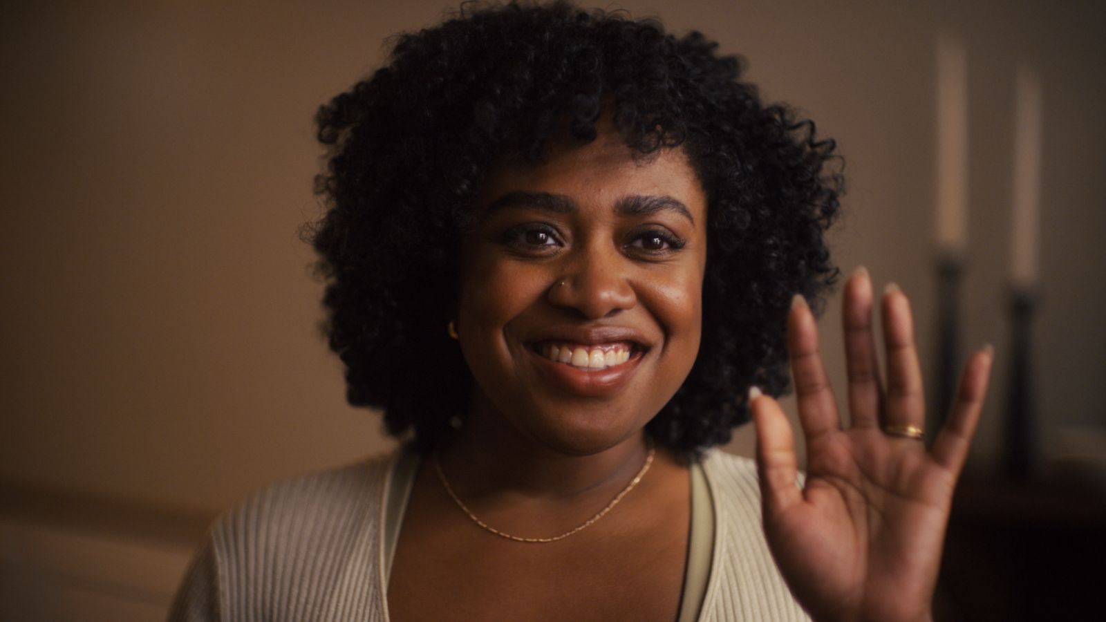 a woman is smiling and waving her hands