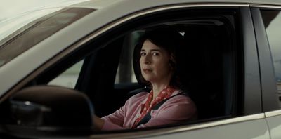 a woman sitting in a car looking out the window