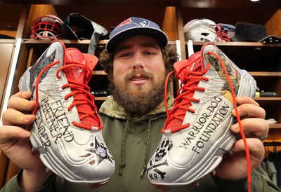 a man holding up a pair of sneakers