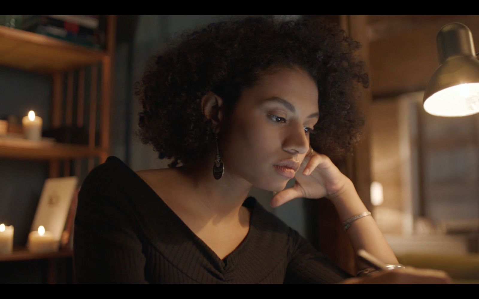 a woman sitting at a table with candles in front of her