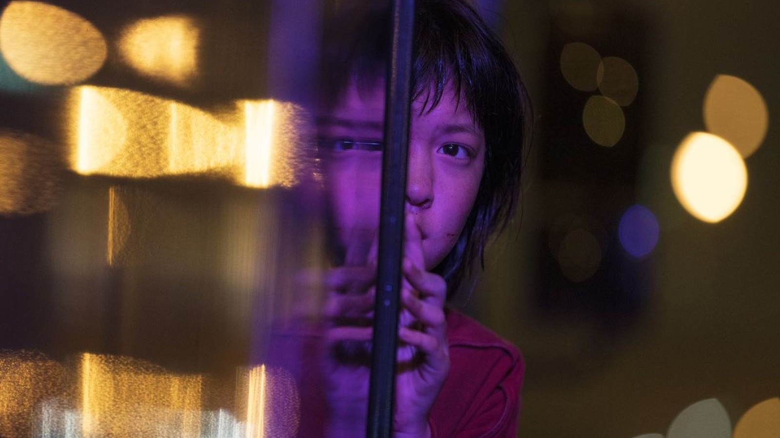 a young boy is looking through a window