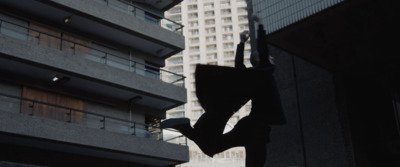 a silhouette of a person holding an umbrella in front of a building