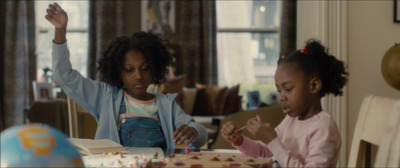 two young girls sitting at a table eating cake