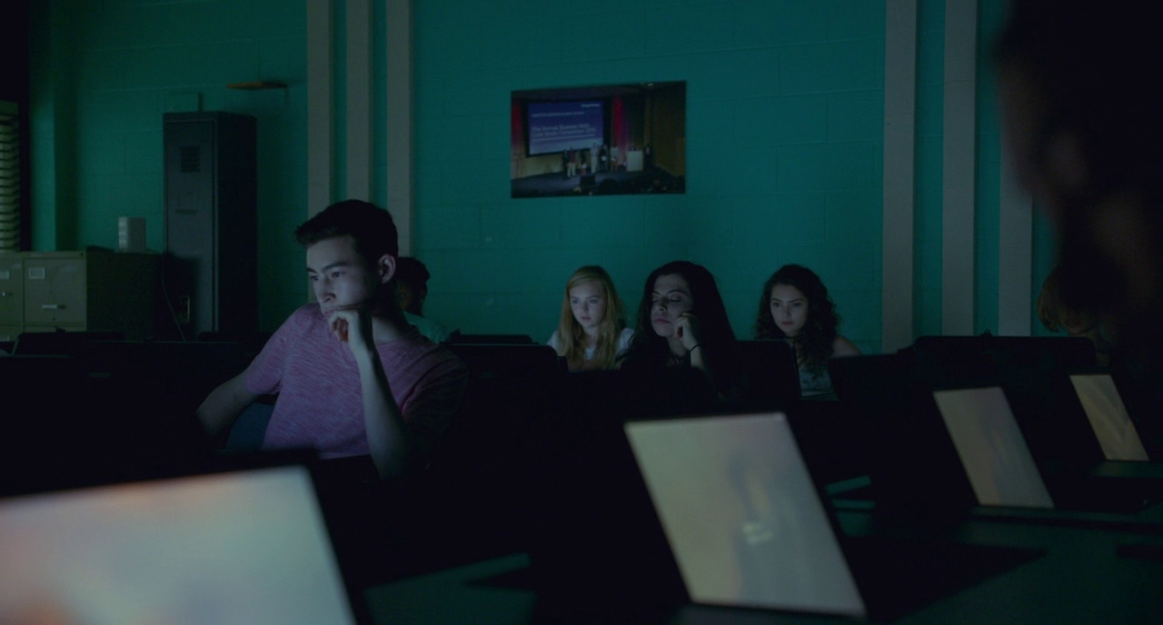 a group of people sitting in a room with laptops