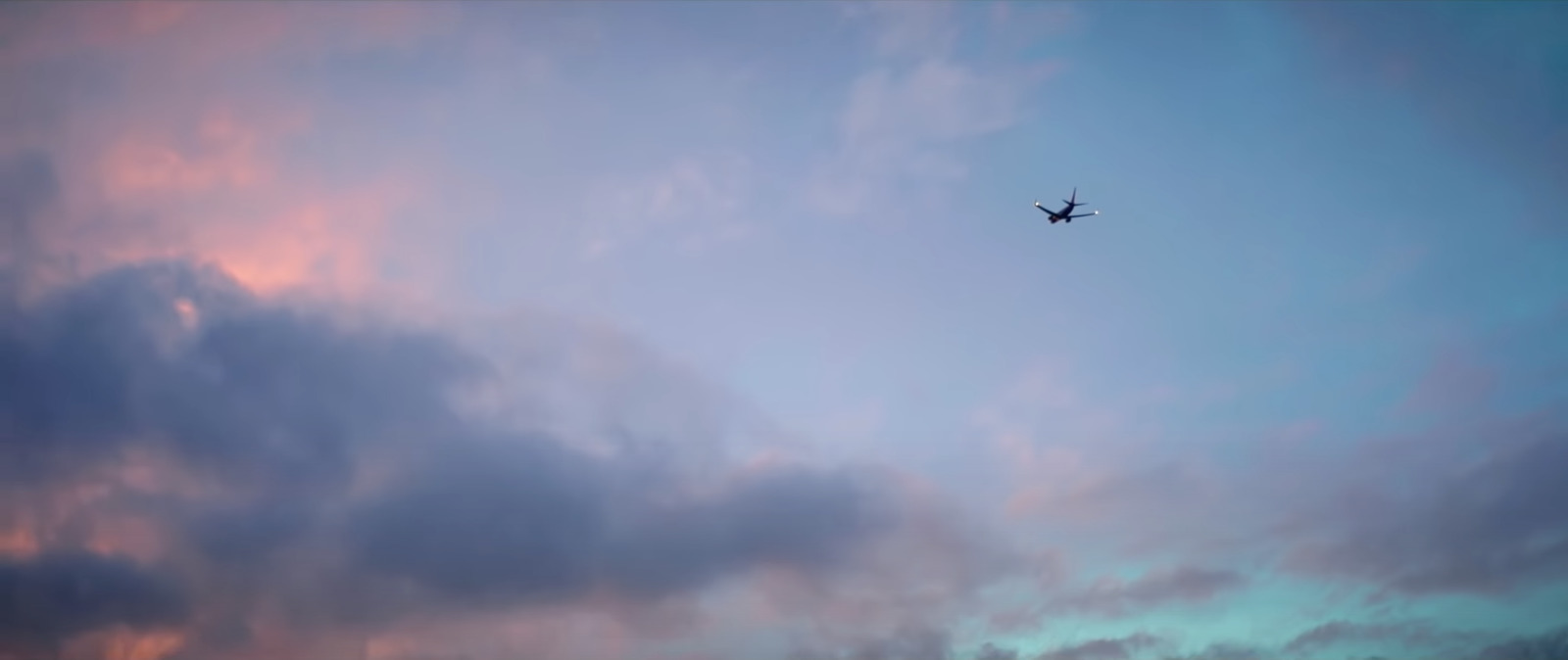 a plane flying through a cloudy blue sky