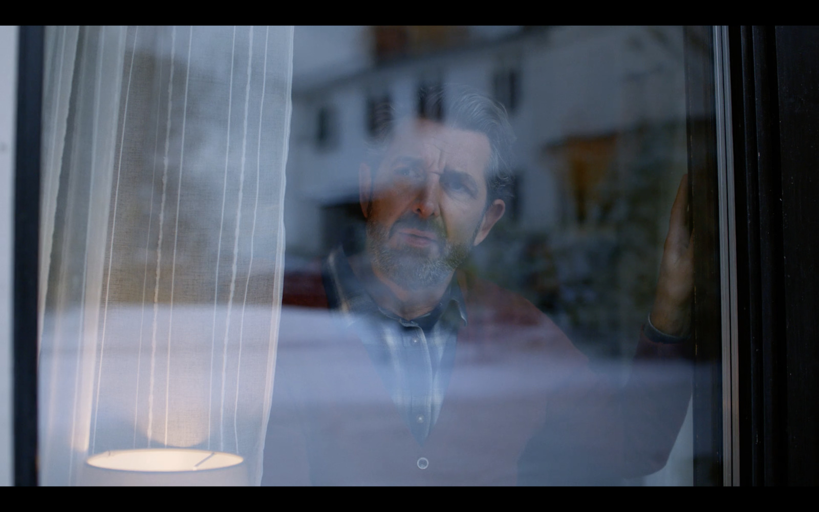 a man looking out of a window at the street