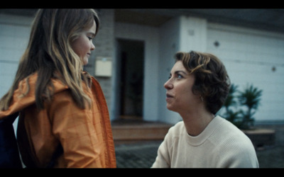 a young girl and a young boy standing outside of a house