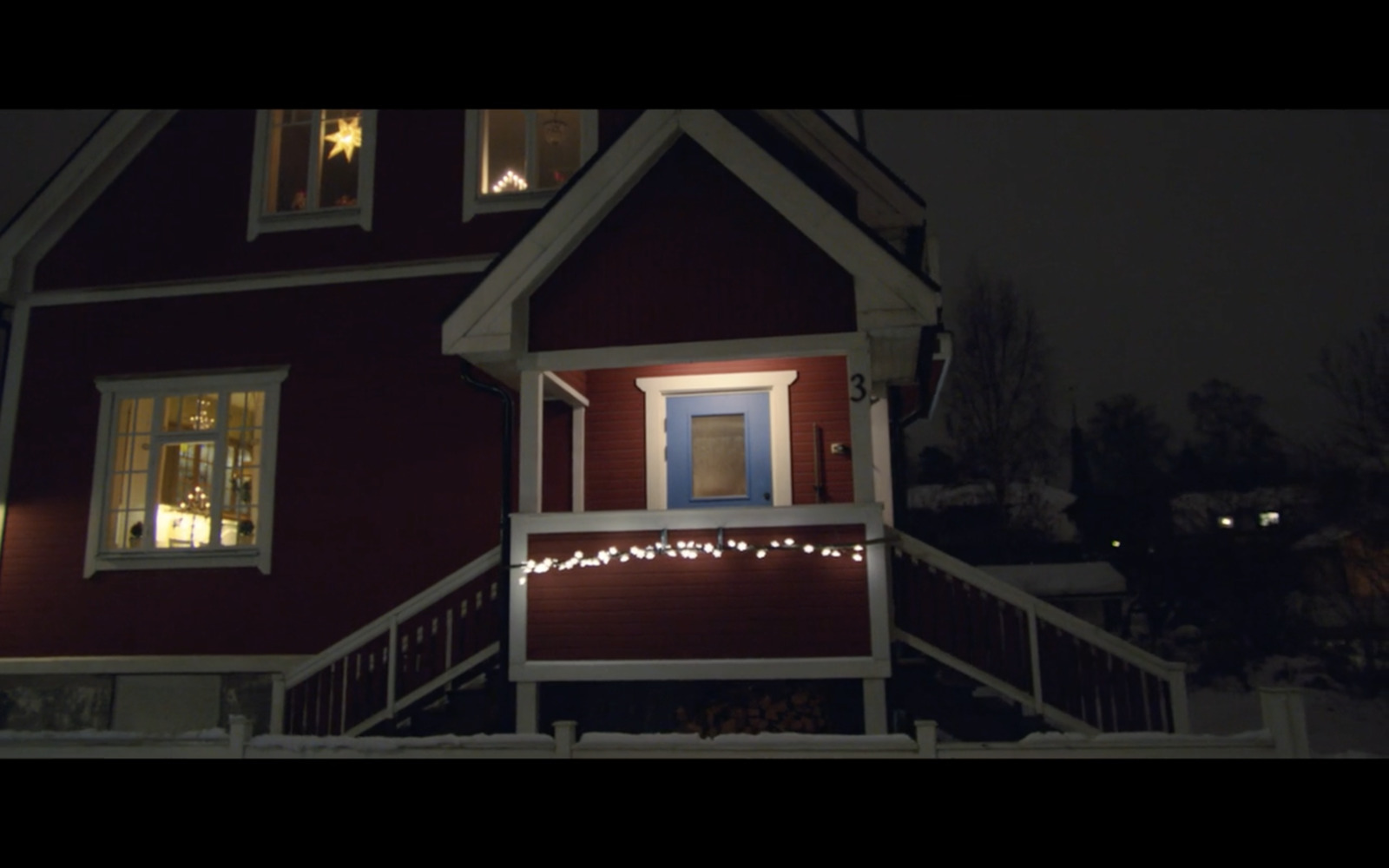 a red house with christmas lights on the porch