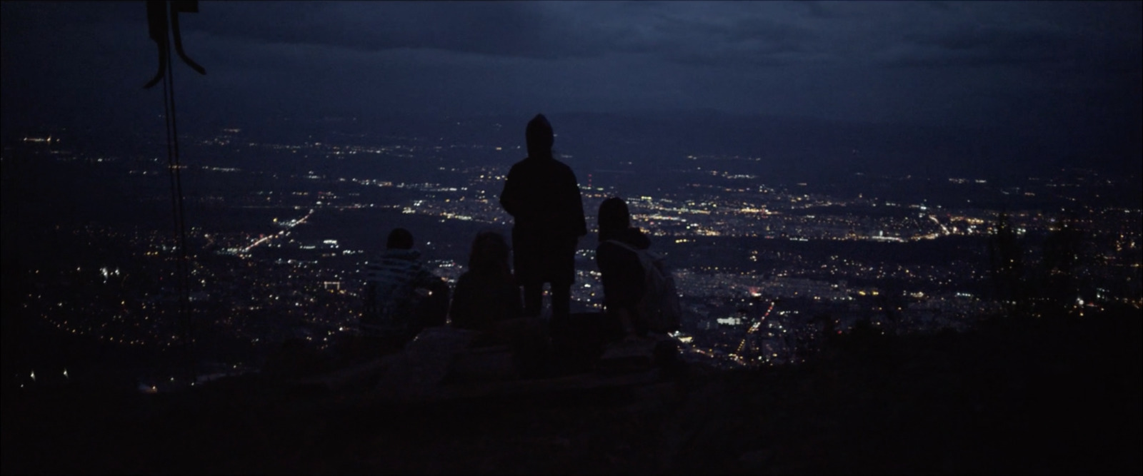 a group of people standing on top of a hill at night