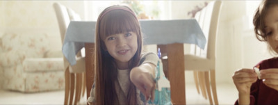 a little girl sitting at a table with a fork in her hand