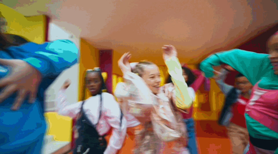 a group of young women dancing around a room