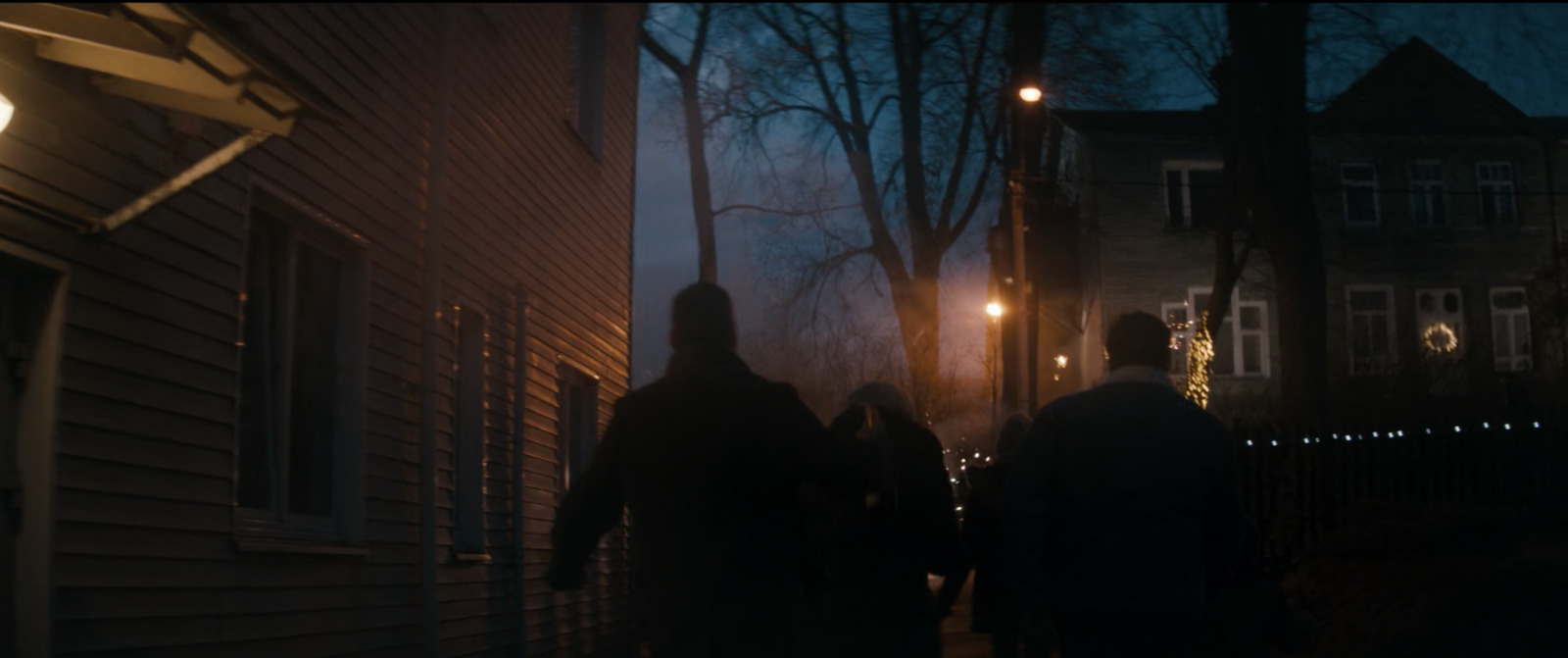 a group of people walking down a street at night