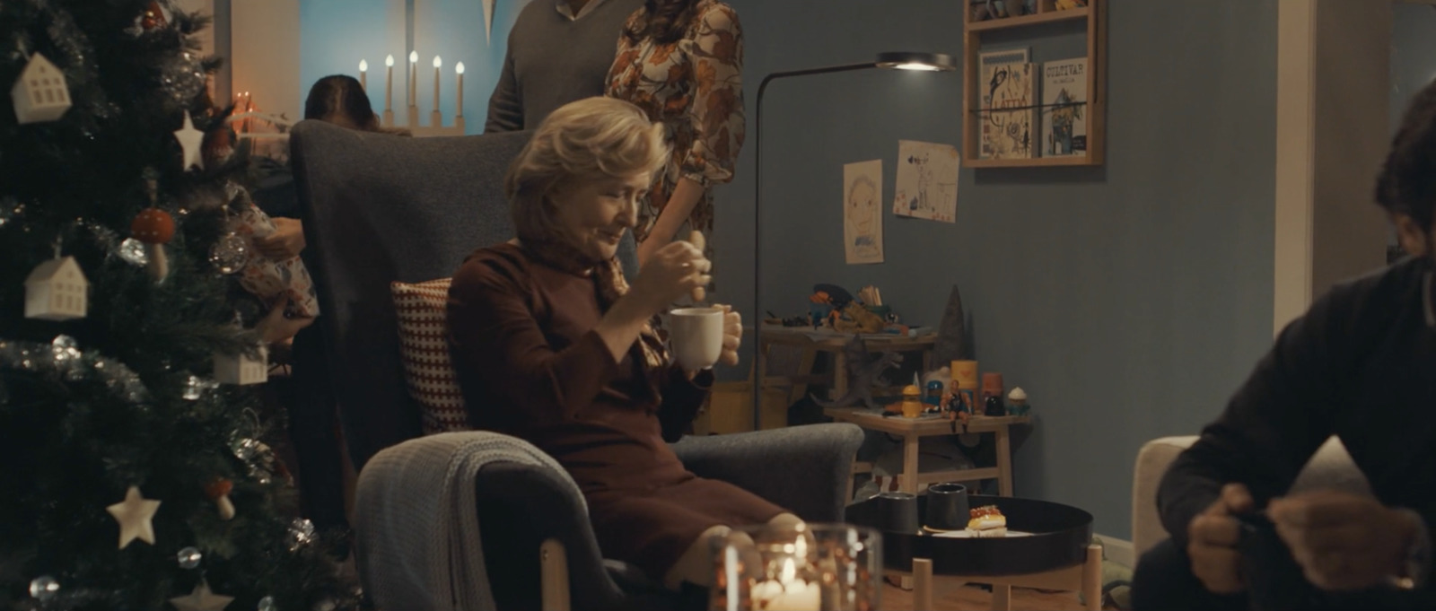 a woman sitting in a chair next to a christmas tree